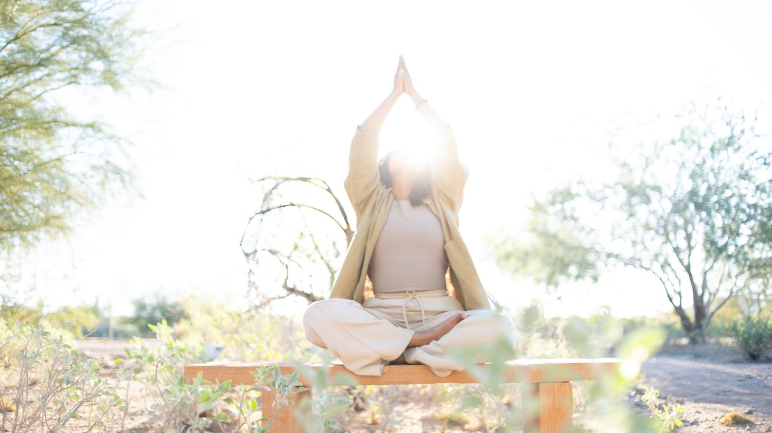 A person in prayer pose, hands raised overhead