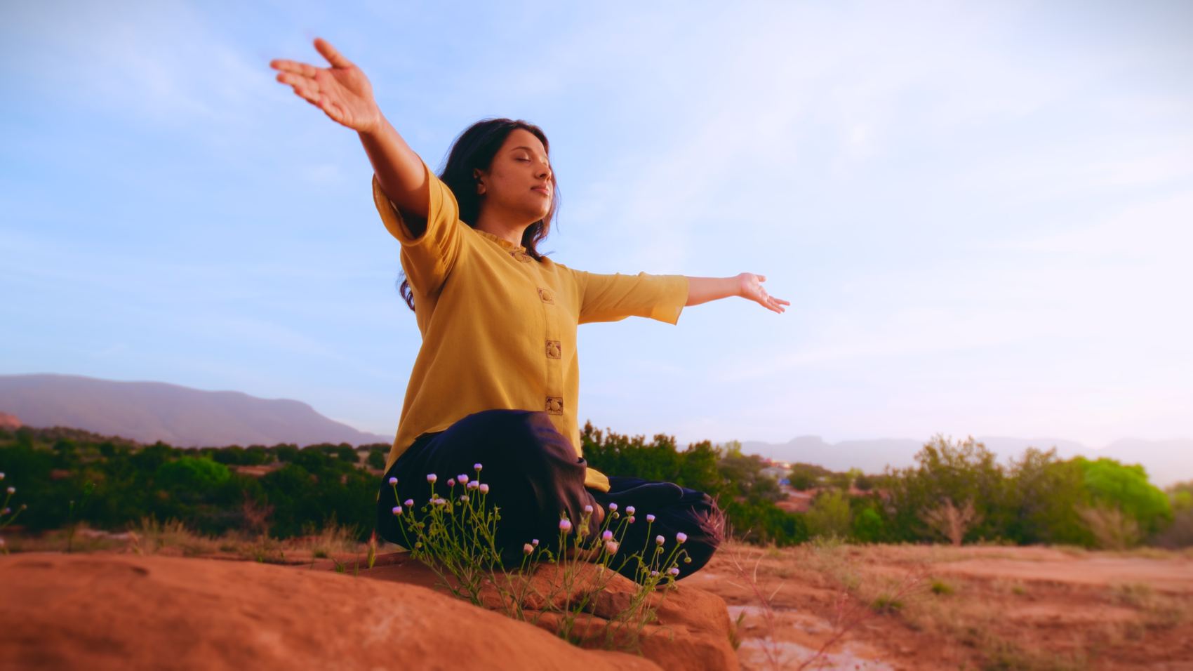 Woman with arms raised in a desert energy practice